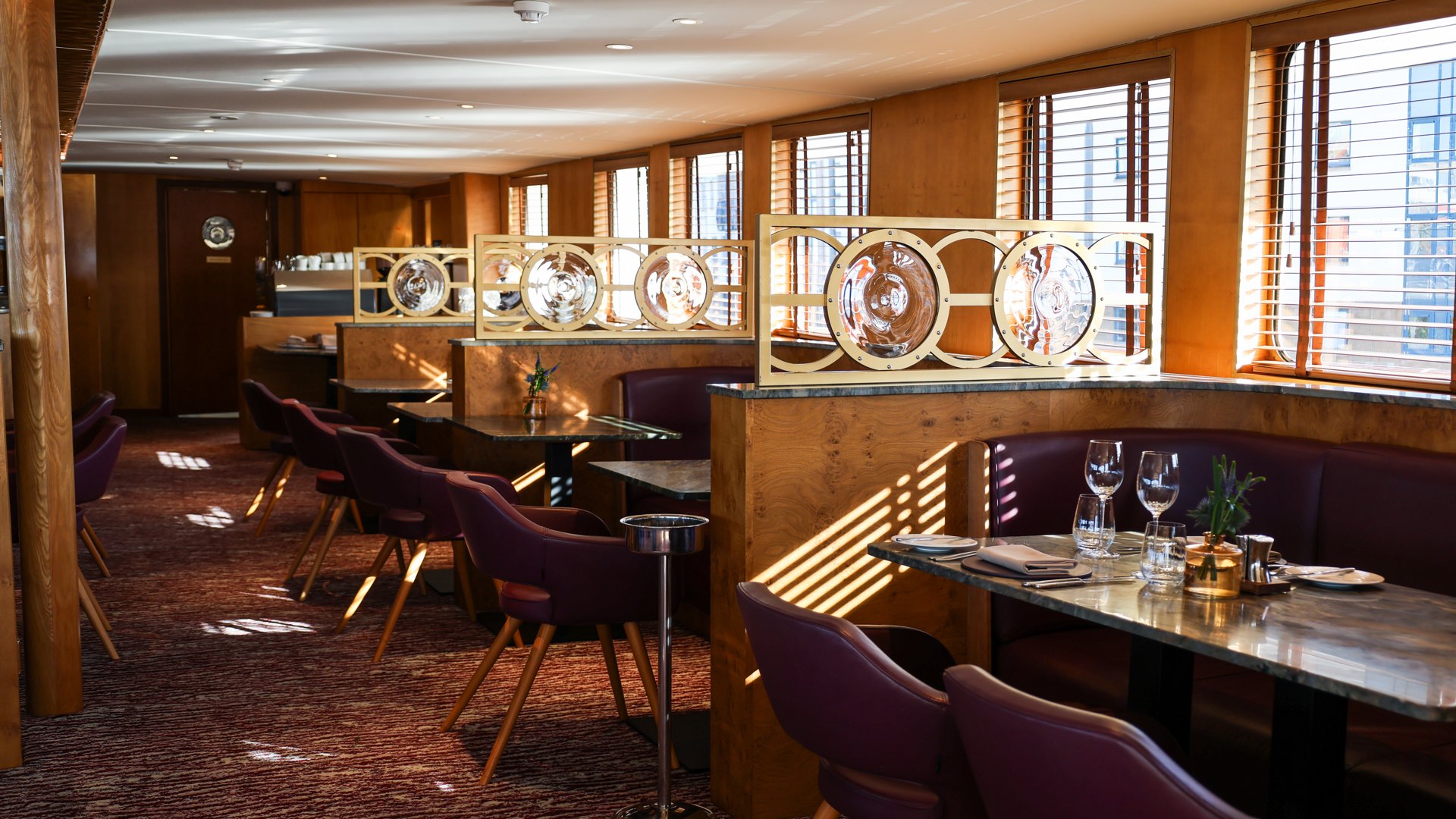 The dining room aboard Fingal: booths, porthole screens and sunlight through the blinds