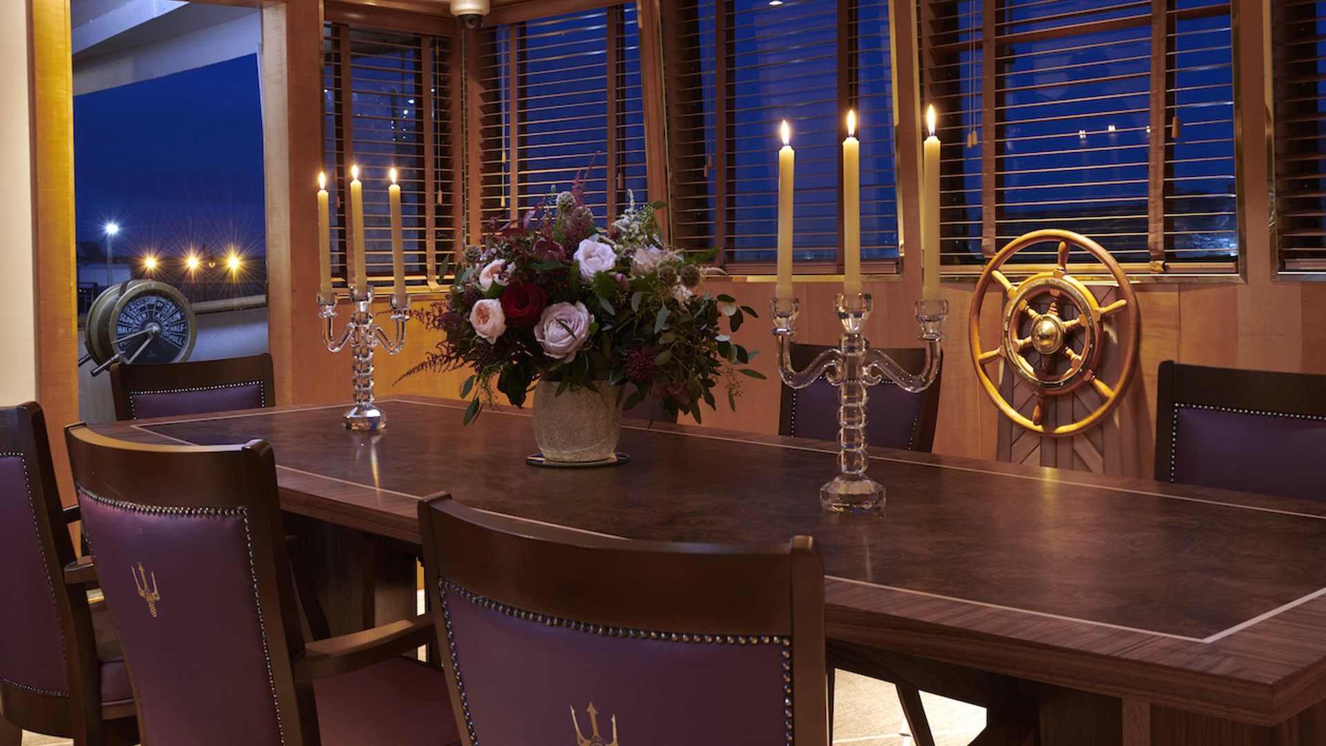 A table set with candelabra and the ship’s wheel in the Bridge room on Fingal