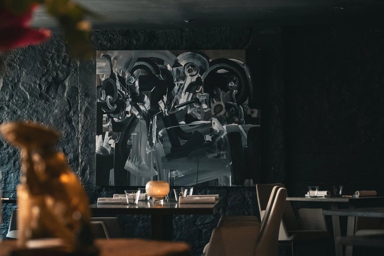 Avery’s dining room: a large abstract painting on a dark stone wall above the tables